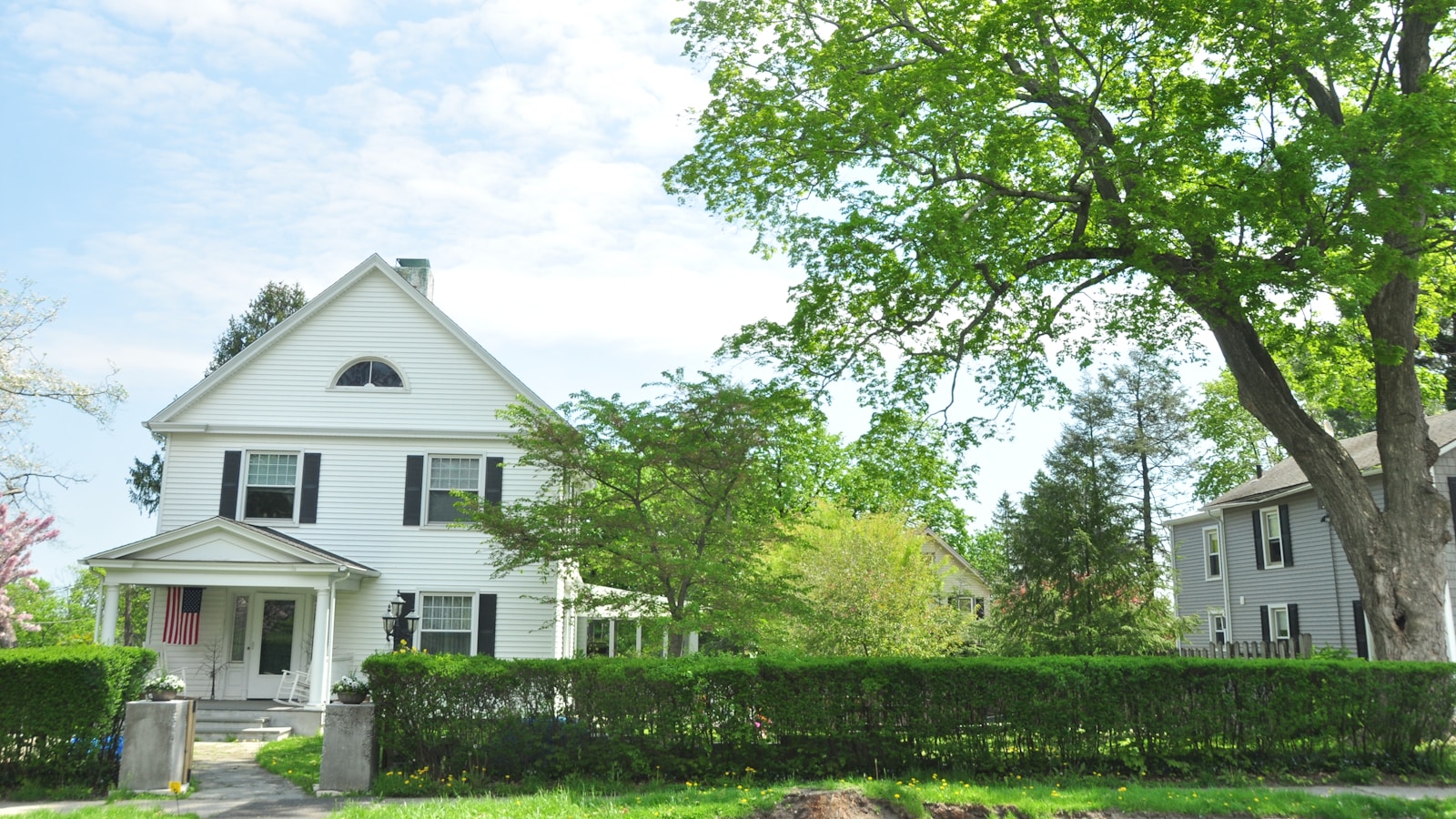 A tidy New England house with white siding and black shutters